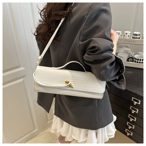 White faux crocodile leather handbag with gold twist-lock shown on a stylish model