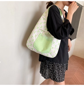 Detail view of floral canvas tote bag with a green plaid pocket and bow pattern print