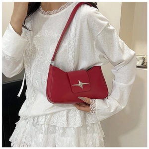Détail du sac à bandoulière en cuir rouge brillant avec boucle métallique en forme d'étoile