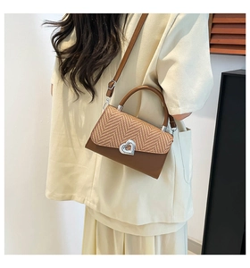 Detail of vintage patchwork crossbody bag with straw texture and silver heart lock
