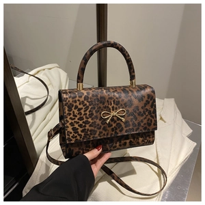 Close-up of leopard print handbag featuring a golden bow buckle and leather texture