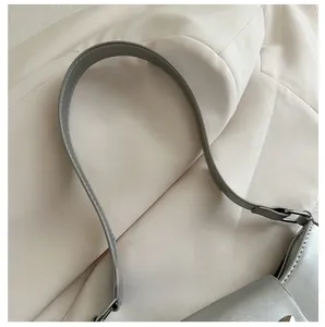 Close-up of silver leather handbag strap with white stitching and metal adjustment buckle