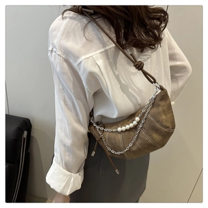 Close-up of brown croissant hobo bag with silver chain and white pearl details