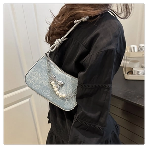 Detail of light blue textured handbag with silver chains, pearls and butterfly charm