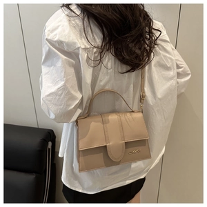Bolso bandolera de piel sintética beige con asa superior mostrado por una modelo real