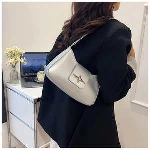 Sac baguette argenté avec boucle étoile porté par un mannequin dans un bureau moderne