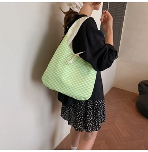 Detail of green and white gingham tote bag featuring a decorative bow tie closure