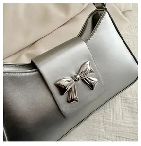 Close-up of silver pearlescent leather shoulder bag with metallic bow detail