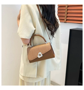 Detail of vintage brown bag with woven flap and heart-shaped silver metal lock