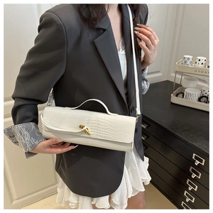 Close-up of white crocodile texture leather bag with gold twist clasp on a model