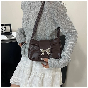 Détail d'un sac à bandoulière marron foncé avec grand nœud plissé et fermoir argenté