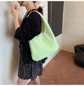 Close-up of green and white checkered canvas tote bag with a decorative bow detail