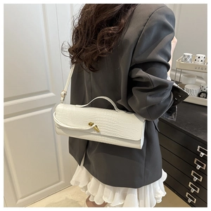 Detail of white crocodile embossed texture and gold twist lock on women's handbag