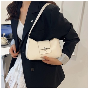 Détail d'un sac sous les bras en cuir crème avec boucle étoile argentée et fine bandoulière