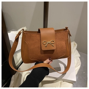 Detail of vintage brown suede shoulder bag with golden bow buckle and wide strap