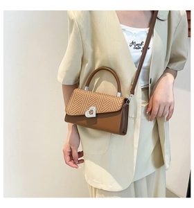 Detailed view of brown leather woven crossbody bag with a silver heart lock on a model