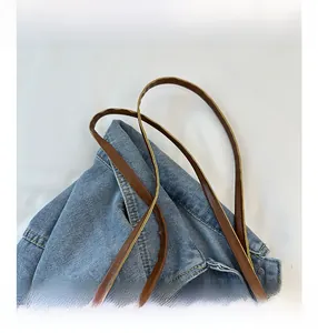 Detail of woven denim tote bag with brown leather strap and contrast stitching