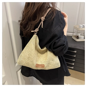 Detail of woven straw tote bag with brown leather FASHION tag and knotted strap