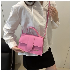 Detalle del bolso bandolera rosa con logotipo metálico y correa ajustable