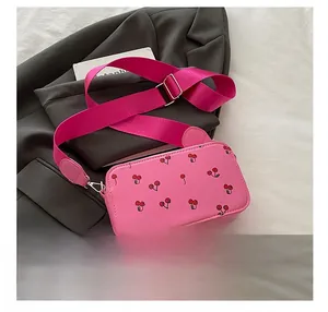 Detailed macro view of pink square crossbody bag with cherry prints and wide fabric strap