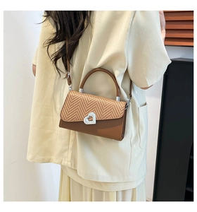 Detail view of retro crossbody bag with straw patchwork and silver heart clasp on model