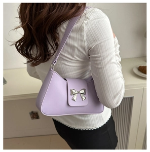 Lavender faux leather baguette bag with silver bow detail worn over the shoulder