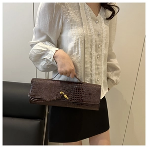 Detail of dark brown crocodile texture handbag with elegant gold twist lock closure