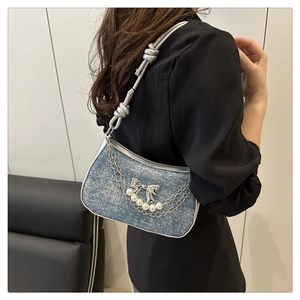 Detail showing denim shoulder bag with silver chains, pearls and butterfly bow buckle