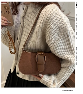 Detail of vintage brown suede underarm bag with metal buckle on beige knit outfit