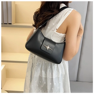 Détail d'un sac baguette chic en cuir noir avec une boucle étoile argentée sur l'épaule