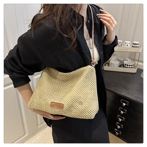 Detail of beige woven straw tote with brown leather label and intricate hollow mesh texture