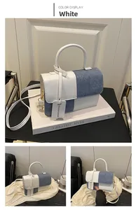 Detail view of white and denim blue patchwork handbag with a top handle and shoulder strap