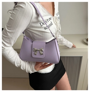 Detail of lilac leather saddle bag featuring a large silver metallic bow decoration