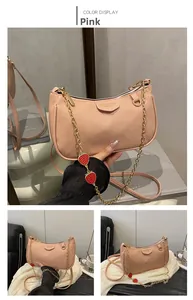 Detail of pink lychee leather handbag with golden chain and cute strawberry pendants