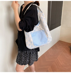 Close-up of floral canvas tote bag with blue gingham pocket worn over the shoulder