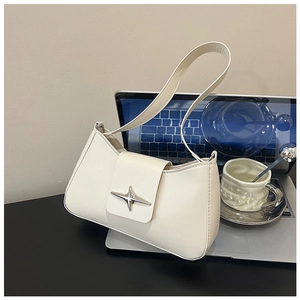Détail du sac baguette blanc en cuir avec boucle étoile dans un bureau