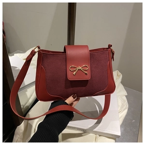 Detail of red leather shoulder bag with suede patchwork and gold bow metal clasp
