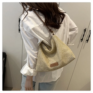 Detail of beige woven straw tote bag featuring brown leather knot strap and fashion patch