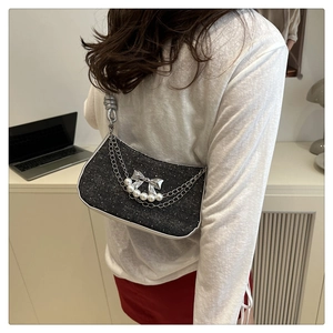 Detail of glitter black shoulder bag with silver bow, pearls, and metallic chains