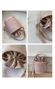 Detail view of pink bucket bag with textured fabric, drawstring closure and gold hardware