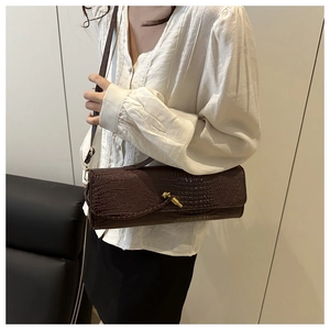 Detail of dark brown faux crocodile leather clutch with gold twist knot lock and thin strap