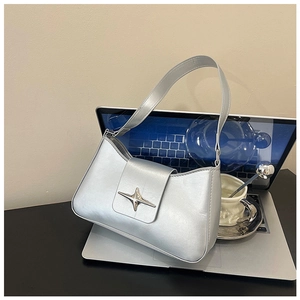 Détail du sac argenté métallisé avec boucle étoile posé sur un bureau d'ordinateur