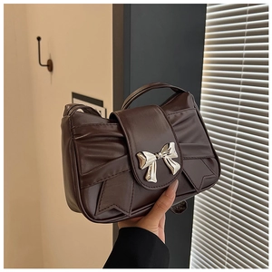 Detail of chocolate brown pleated PU leather bag with silver metal bow decoration