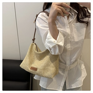 Detailed texture of hand-woven straw bag featuring a brown leather strap and fashion label