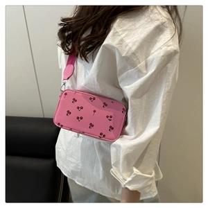 Détail du sac bandoulière rose avec motifs cerises rouges et large bandoulière