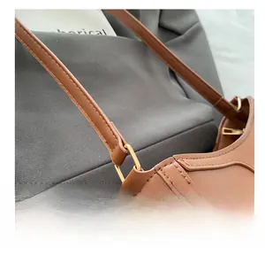 Detail view of brown faux leather shoulder bag with fine stitching and gold metal ring