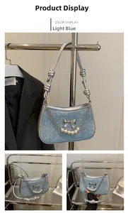 Detail of light blue crossbody bag with silver bow, pearls, and metallic chain accents
