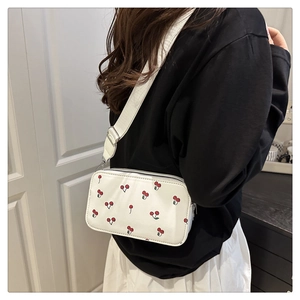 White PU leather saddle bag with red cherry pattern and adjustable wide strap