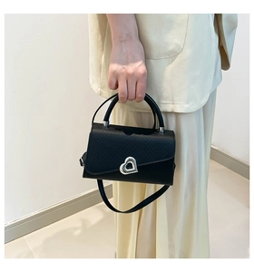 Close-up of black crossbody bag with silver heart-shaped metal twist lock and PU leather texture