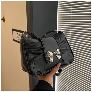 Detail of black matte handbag with pleated design and silver metal bow buckle accent